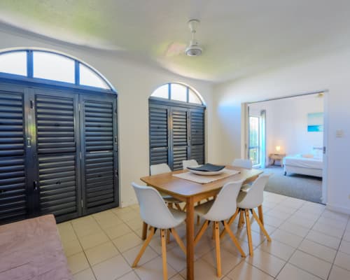 Courtyard of a 1 or 2 bedroom apartment at Mango Lagoon Resort, Palm Cove Cairns, showing dining area, bedroom, and louvre doors