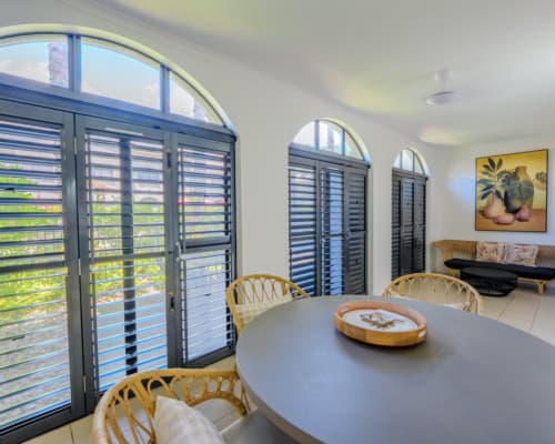 Courtyard of a 1 or 2 bedroom apartment at Mango Lagoon Resort, Palm Cove Cairns, showing dining area, and louvre doors
