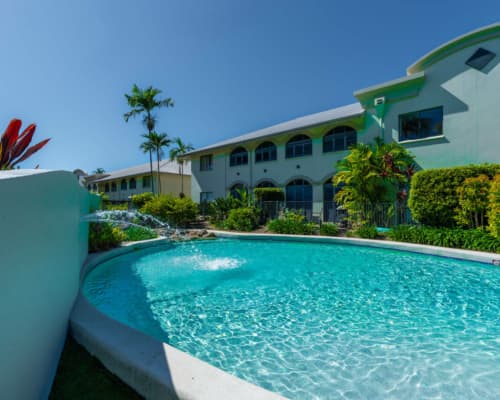 Sparkling swimming pool with fountain at Mango Lagoon Resort, Palm Cove Cairns, surrounded by tropical greenery