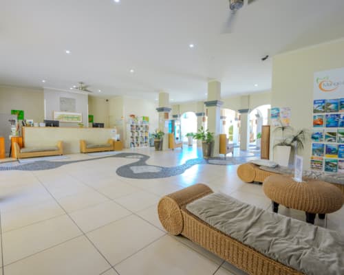Spacious lobby of Mango Lagoon Resort, Palm Cove Cairns, showing reception area and brochures for local tours and attractions