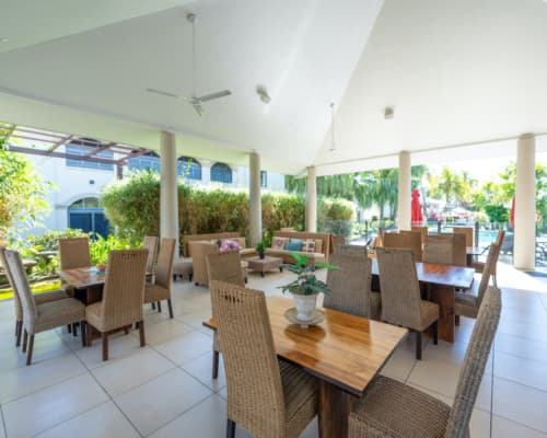 Seating area in the café/bar at Mango Lagoon Resort, Palm Cove Cairns, with open-air sides and views of the pool