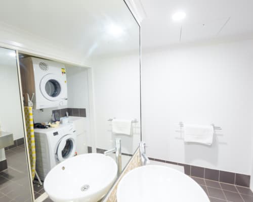 Bathroom with laundry facilities, including washer, dryer, and iron, in a 1 or 2 bedroom apartment at Mango Lagoon Resort, Palm Cove Cairns