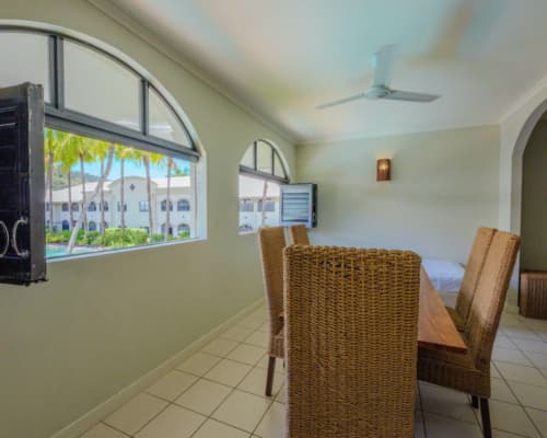 Dining room of a 1 or 2 bedroom apartment at Mango Lagoon Resort, Palm Cove Cairns, with louvre windows open to view the pool area