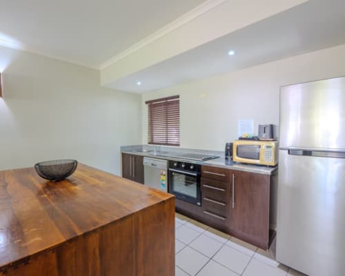 Fully-equipped kitchen in an upper floor 1 or 2 bedroom apartment at Mango Lagoon Resort, Palm Cove Cairns, featuring fridge, oven, microwave, and dishwasher