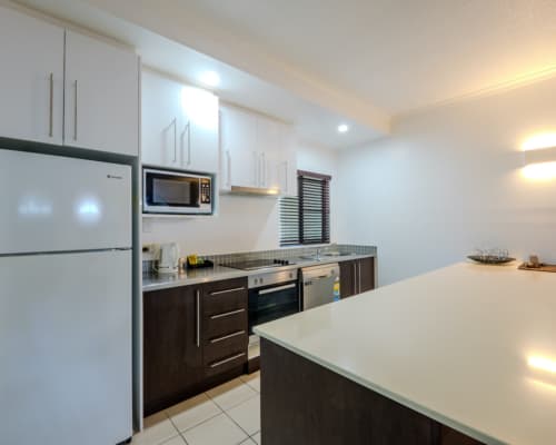 Kitchen in a 1 or 2 bedroom apartment at Mango Lagoon Resort, Palm Cove Cairns, featuring fridge, oven, microwave, and dishwasher